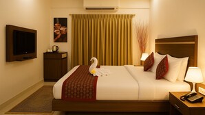 Habitación de hotel con una cama, televisor, escritorio y teléfono, además de un cisne decorativo sobre la cama.