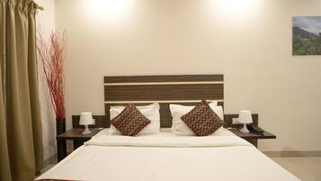 Habitación de hotel con una cama grande, dos mesitas de noche con lámparas, un aparador con teléfono y un cuadro en la pared.
