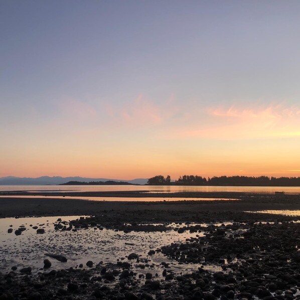 A coastal landscape with rocky terrain and calm waters during sunset.