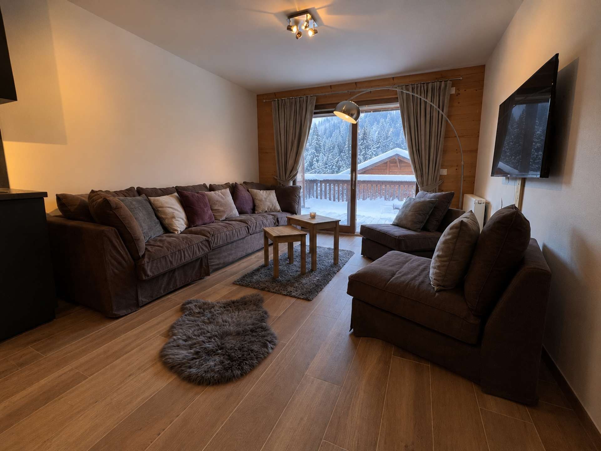 Ein gemütliches Wohnzimmer mit einer braunen Sofagarnitur, einem Holztisch und einem flauschigen Teppich.