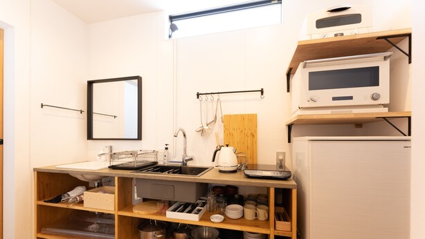 Cocina compacta con microondas, pileta y estantes de madera.