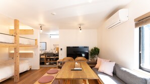 Un espacio habitable compacto con una litera, una mesa de comedor, un sofá y un televisor.
