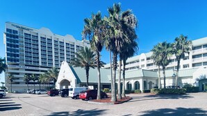 A hotel with a modern design, featuring a large parking area and palm trees. - ~ Shore ~ Thing ~ Studio Condo near The Beach ~ (Daytona Beach)
