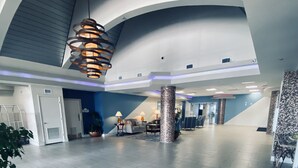 A spacious lobby with a high ceiling, a modern chandelier, and a seating area with tables and chairs. - ~ Shore ~ Thing ~ Studio Condo near The Beach ~ (Daytona Beach)