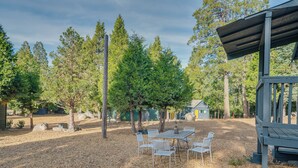 Un espace extérieur aménagé avec une table et des chaises, entouré d’arbres et d’une structure en bois.