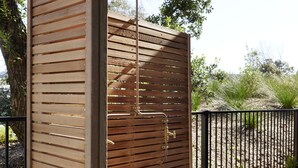 Pantalla de madera para privacidad con un portón de metal y un colgante de luz.