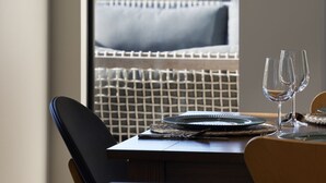 Un comedor con una mesa preparada para dos, con vista a una playa y dunas cubiertas de hierba.