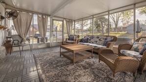 A covered patio with wicker furniture, a woven coffee table, and a patterned rug. - Charming open 4bd and screen-in porch! Sleeps 10! (Saint Charles)