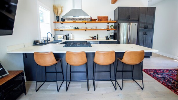 Una cocina moderna con una isla central, taburetes de bar y electrodomésticos integrados.