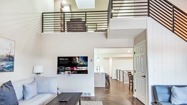 A modern living room with a sofa, coffee table, and a TV wall art. - Canyon View Ski House | Sleeps 14 + Hot Tub (Cottonwood Heights)