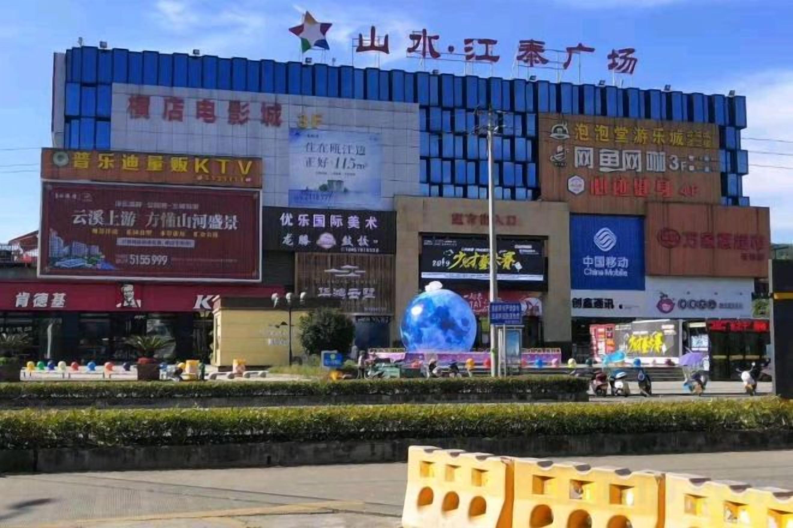 A commercial building with multiple advertisements and a large blue spherical sculpture in front.
