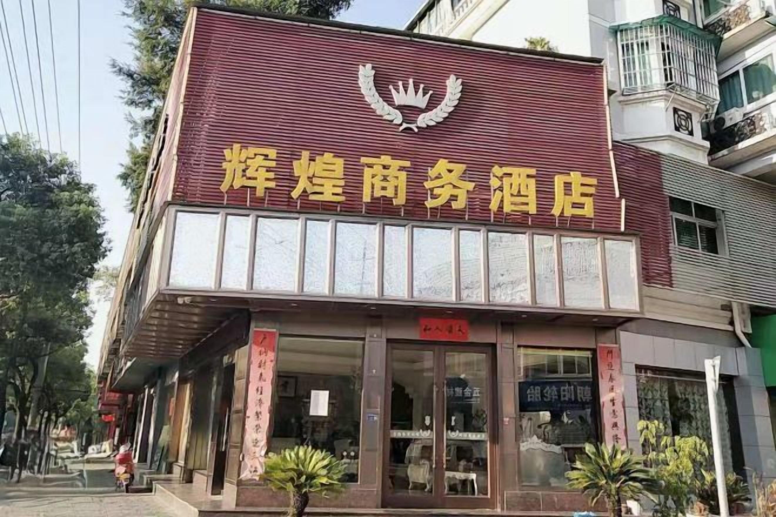 Un edificio con un letrero llamativo en caracteres chinos, un balcón en el piso superior y un escaparate con ventanas de vidrio.