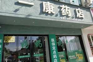 A pharmacy with large windows and a green signboard.