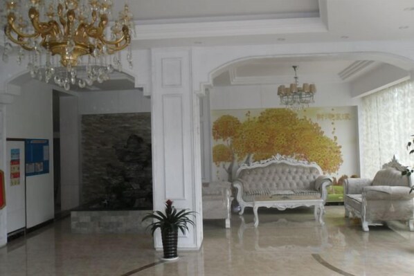A spacious lobby with a grand chandelier, a stone fireplace, and a large floral mural.