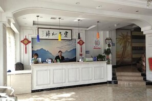 A reception desk with a framed picture above it, a staircase to the right, and a plant on the desk.