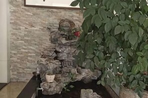 Una pared de piedra con una fuente de agua y una planta en maceta.