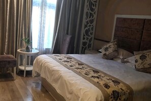 Une chambre d’hôtel avec un lit, une petite table ronde ornée d’une plante et une vue sur l’extérieur.
