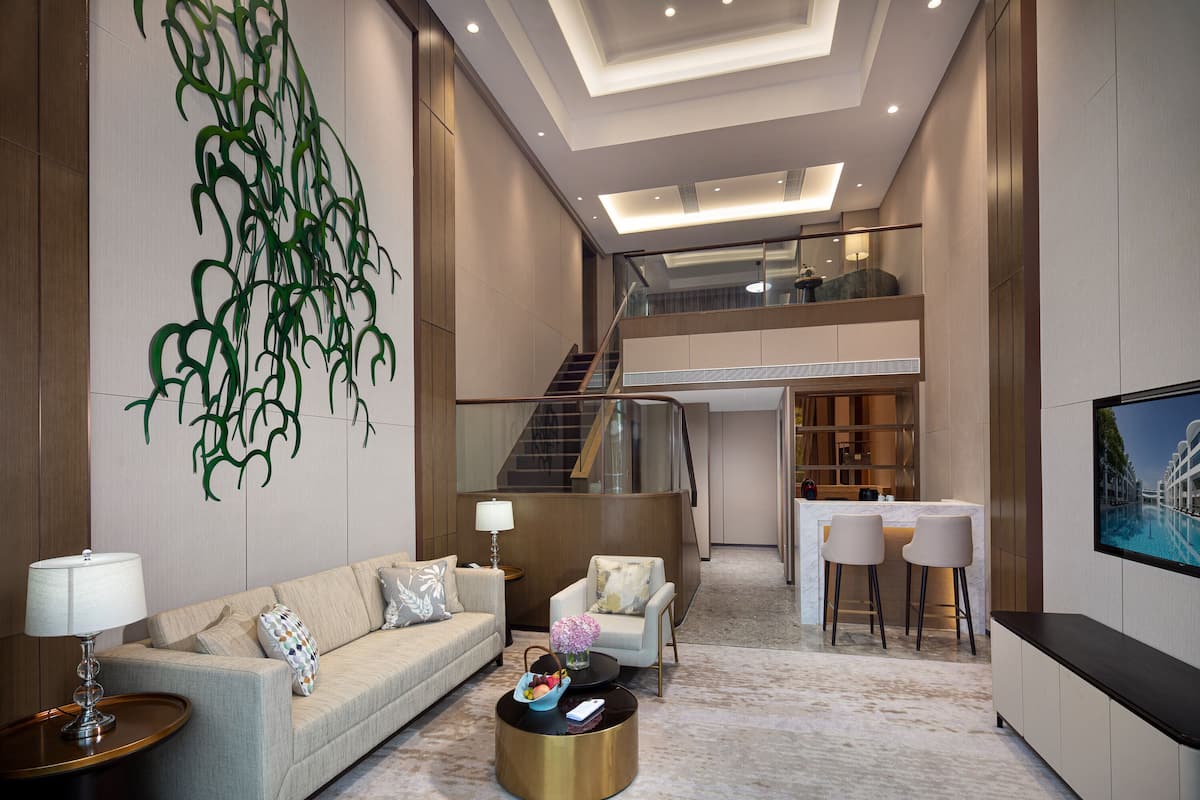 A spacious living area with a sofa, coffee table, and a TV. A staircase leads to an upper level.