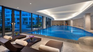 Ein modernes Hallenbad mit Liegestühlen und Blick ins Freie.