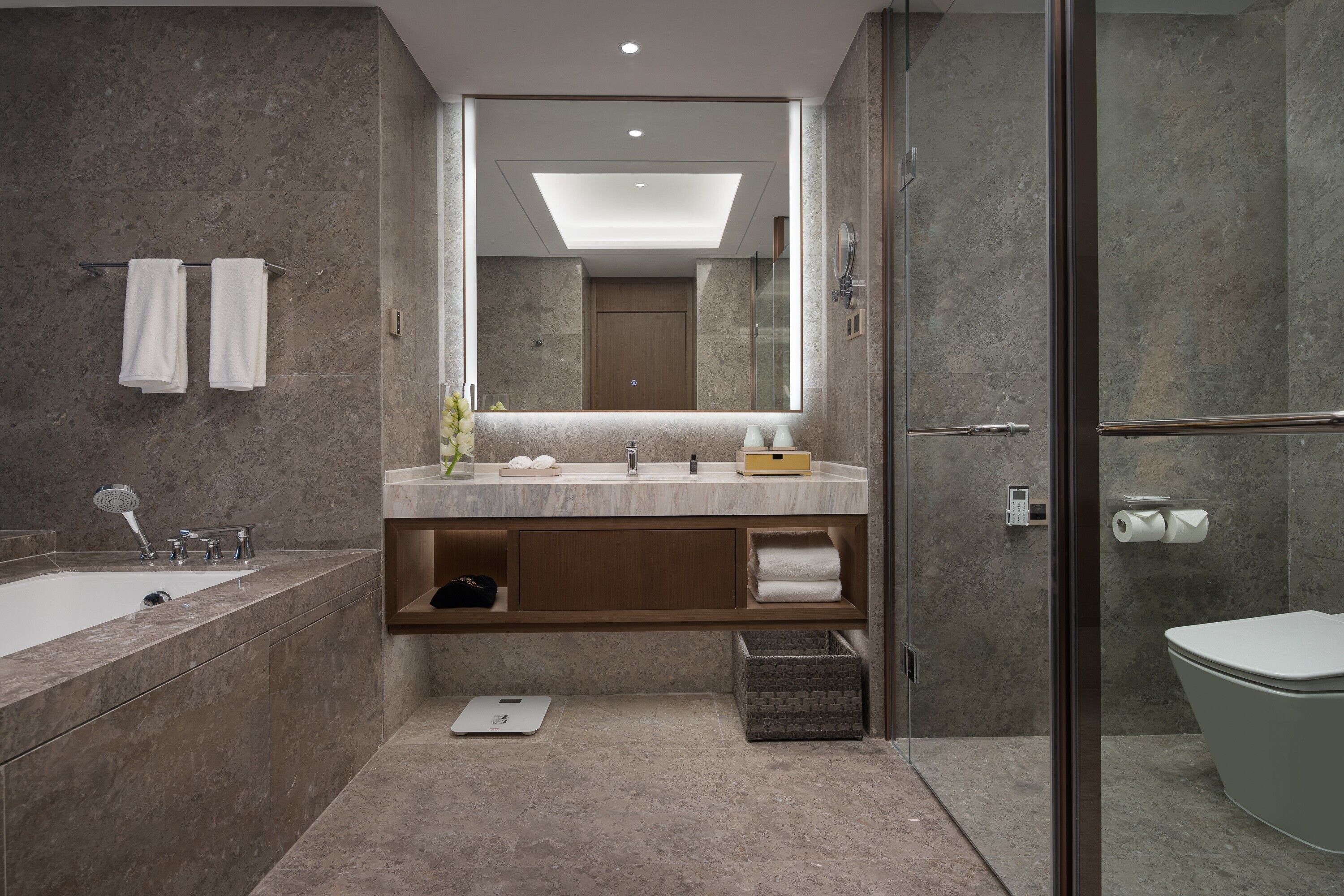 Une salle de bain moderne avec un grand miroir, une baignoire, une douche et des toilettes.
