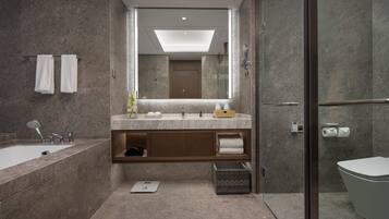 Un baño moderno con un espejo grande, una bañera, una ducha y un inodoro.