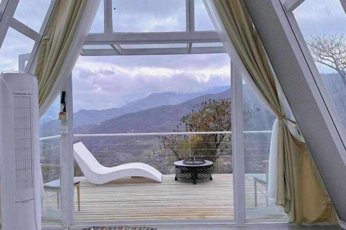 Une pièce avec vue sur les montagnes, une chaise blanche, une table ronde et un appareil de climatisation blanc.