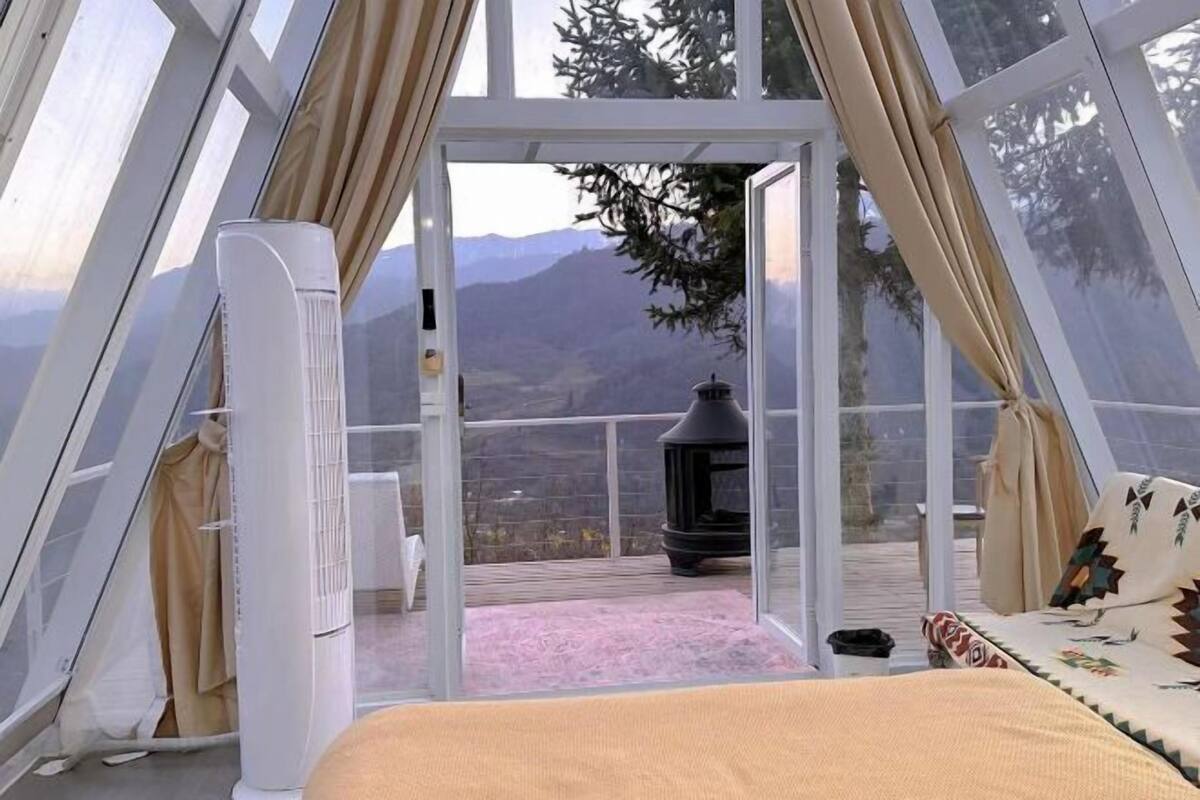 Une chambre avec un lit, un radiateur et une vue sur les montagnes, visible à travers une porte vitrée.
