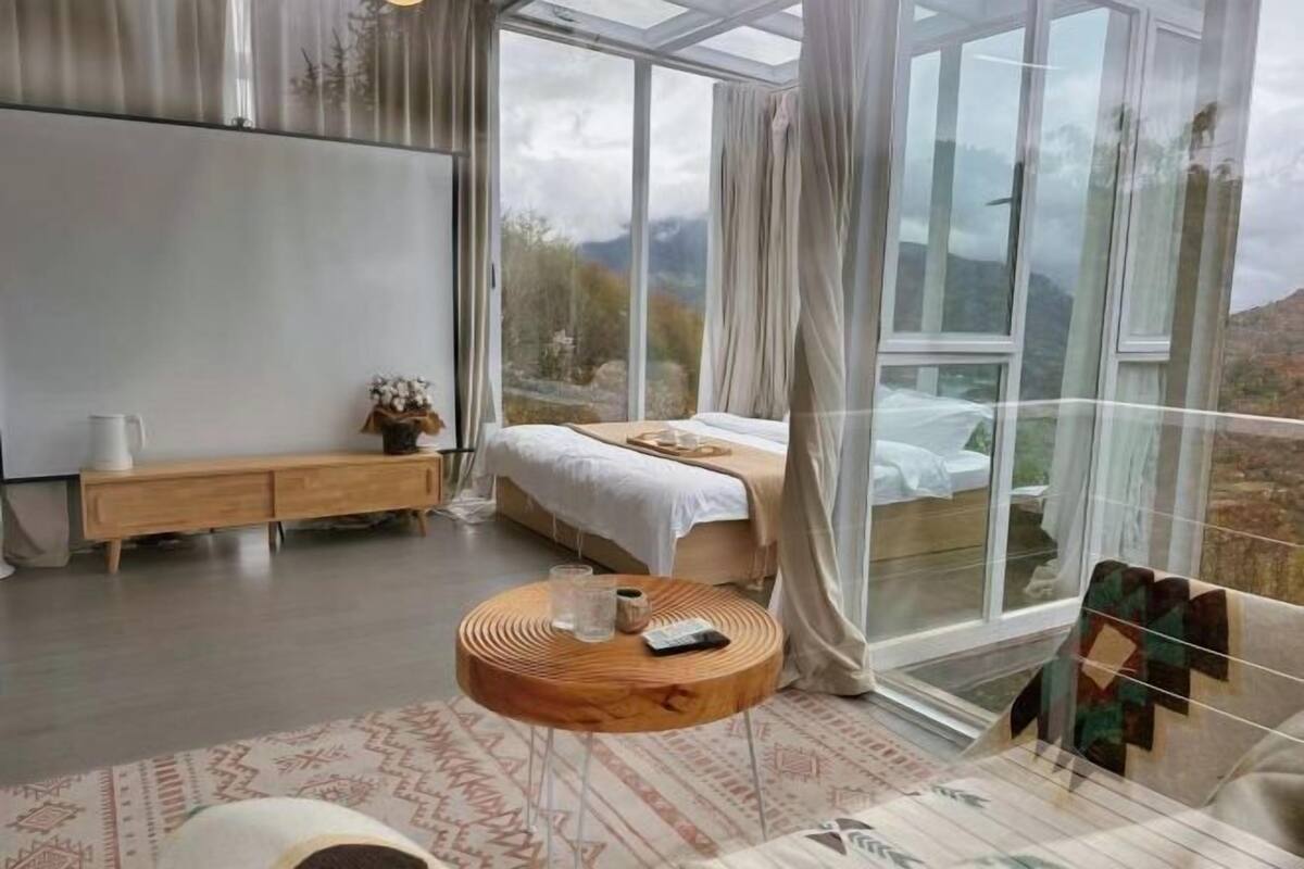 Une chambre moderne avec une grande fenêtre, un lit, une table de chevet et une table ronde en bois.