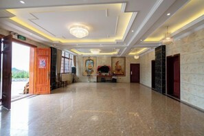 A hotel lobby with a marble floor, a chandelier, and artwork on the walls.