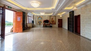 Un hall d’entrée spacieux, doté d’un sol en marbre poli, d’un lustre et d’une grande statue de Bouddha.