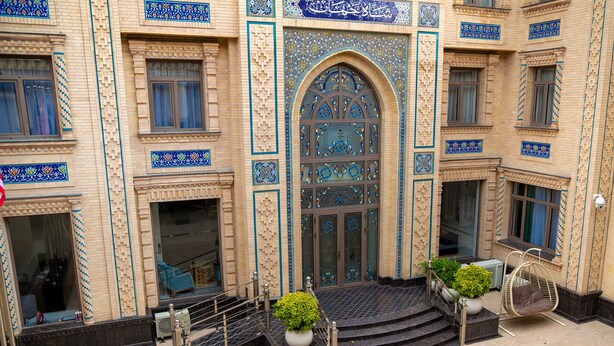 Un edificio con una entrada imponente, una escalera que conduce a la entrada y un sillón colgante en el exterior.