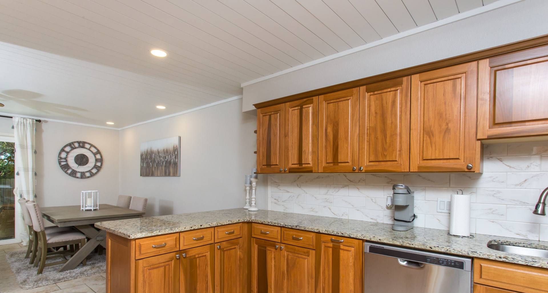 A kitchen with wooden cabinets, a granite countertop, a dishwasher, and a coffee maker.