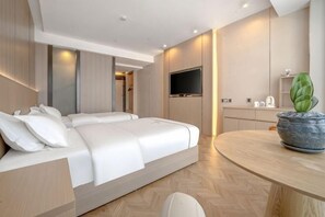 A modern hotel room with a large bed, a round dining table, a flat-screen TV, and a potted plant. - Jinxi Hotel (Olympic Sports Center Geological Museum Branch) (Guiyang)