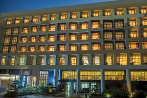 Un hôtel  à plusieurs étages, doté d’une façade uniforme, de grandes fenêtres et d’une entrée bien éclairée.
