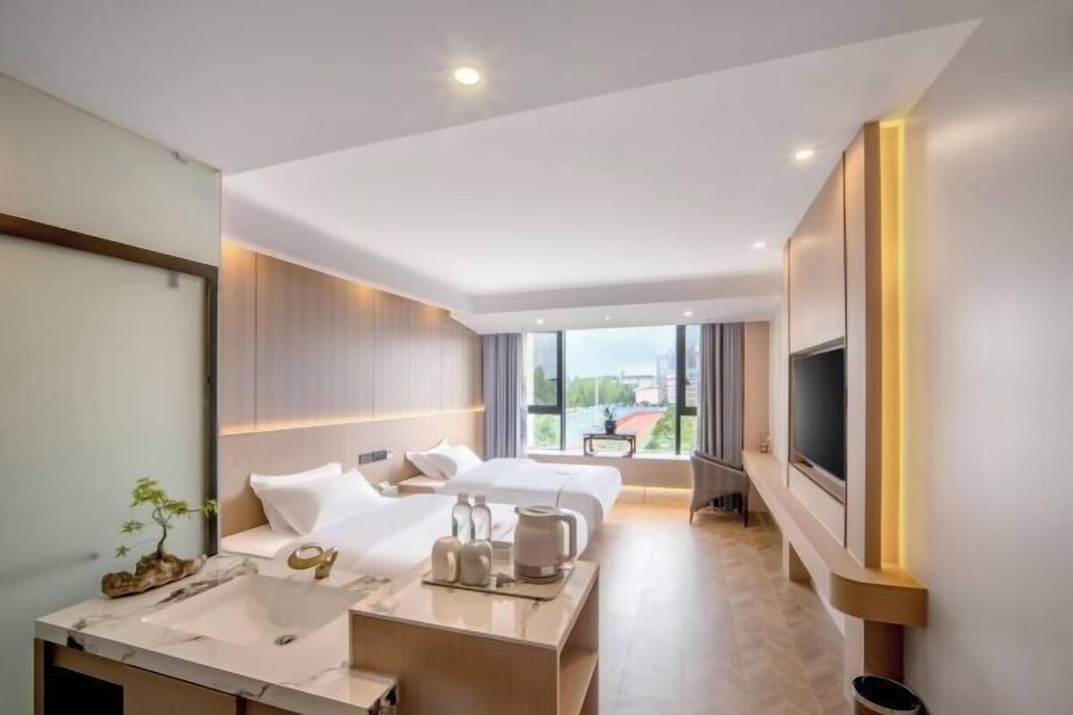 Een moderne hotelkamer met een groot bed, een zithoek, een televisie en een badkamer met een wastafel en spiegel.