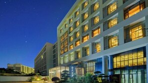 Um hotel moderno com vários andares, janelas amplas e fachada bem iluminada.