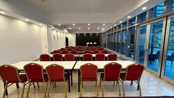 A conference room with a long table and red chairs, large windows, and a stage.