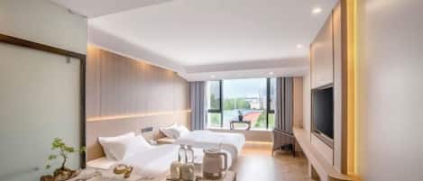 A modern hotel room with a large bed, a separate seating area, a TV, and a bathroom with a sink and mirror.