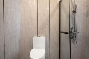 A modern bathroom with a white toilet, a glass-enclosed shower, and marble walls. - Jinxi Hotel (Olympic Sports Center Geological Museum Branch) (Guiyang)