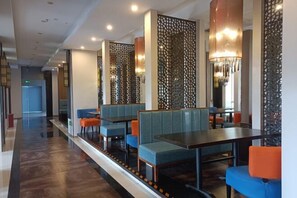 A modern restaurant with booths and tables, decorative wall panels, and ambient lighting.