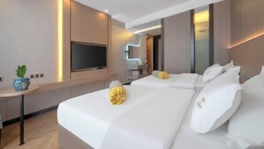 Quarto de hotel moderno com uma cama grande, televisão de tela plana e uma pequena mesa com uma planta.