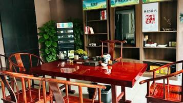 A dining area with a wooden table and chairs, surrounded by bookshelves and decorative items.
