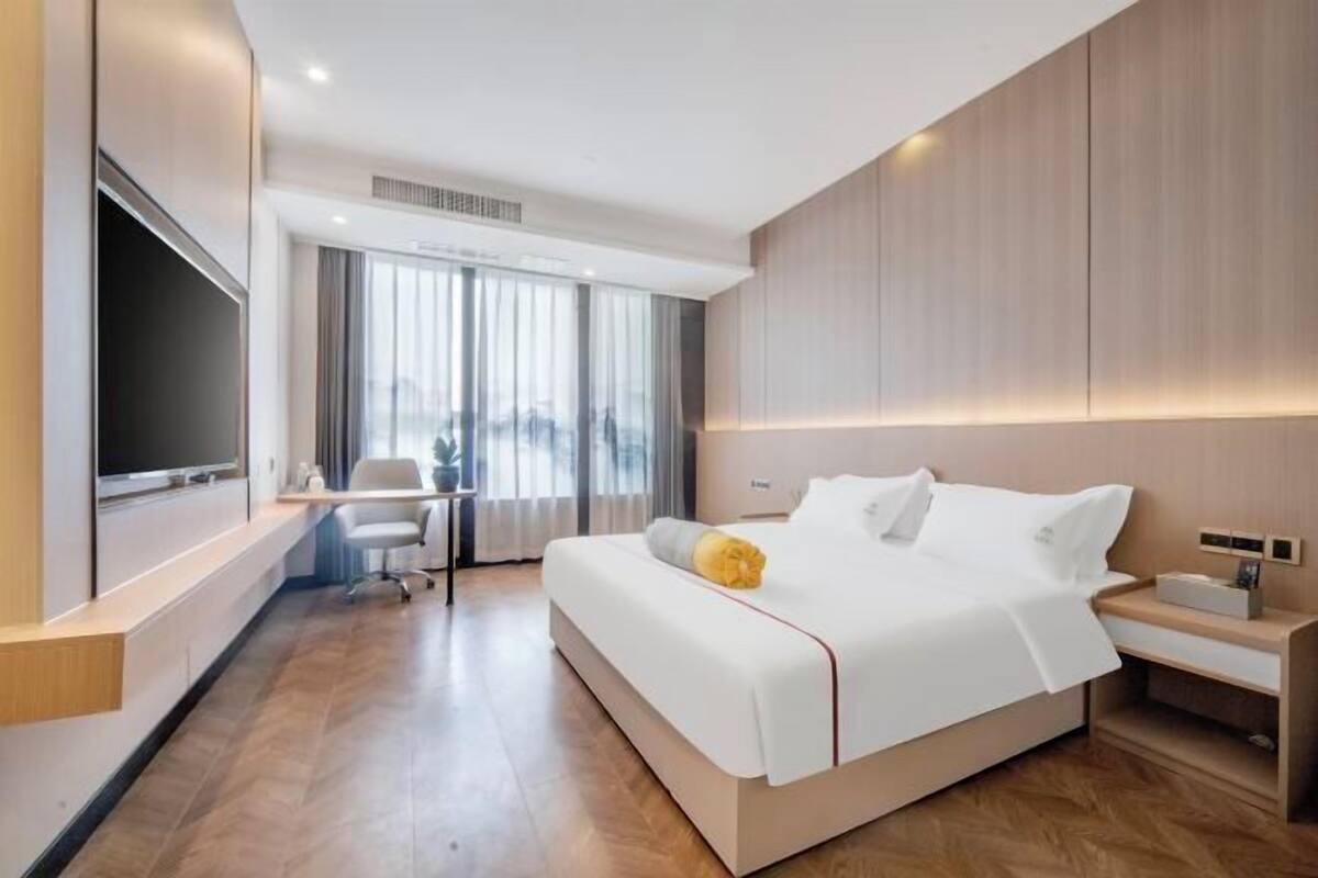 Een moderne hotelkamer met een groot bed, een bureau en een televisie.