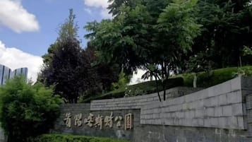 A stone wall with a sign, surrounded by greenery and trees.