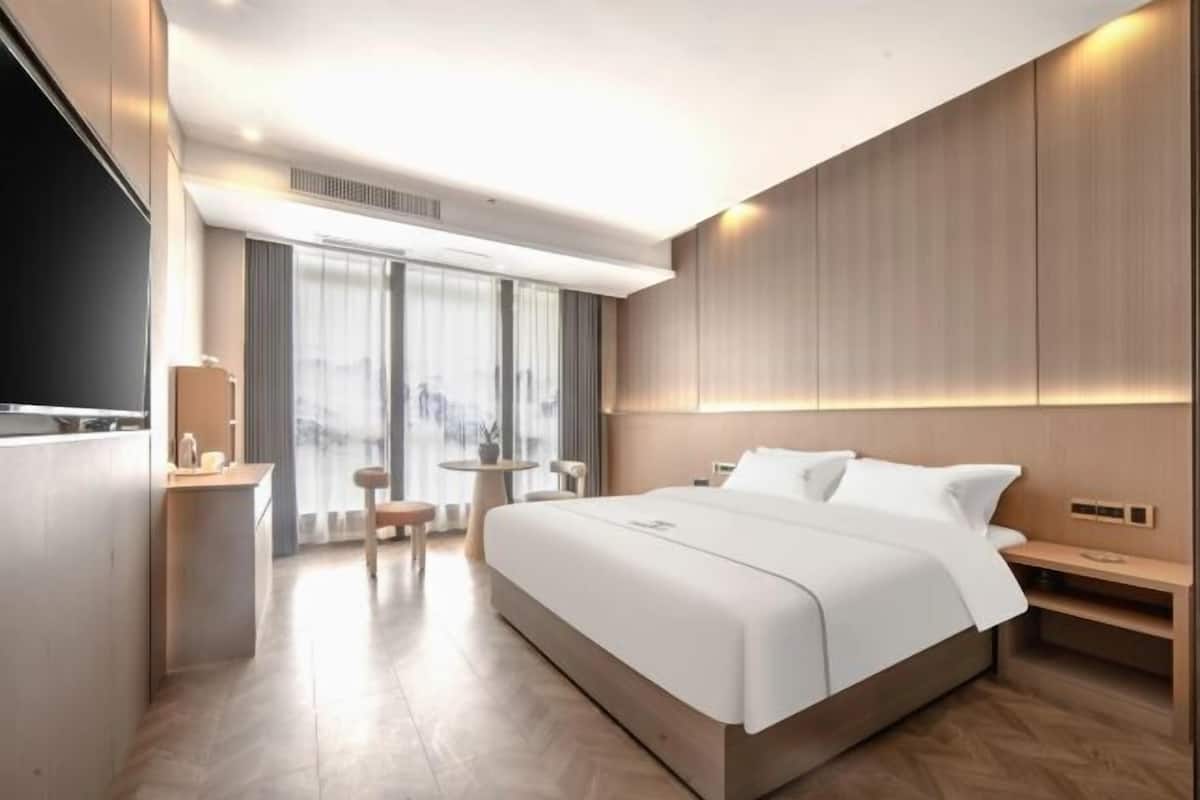 Een moderne hotelkamer met een groot bed, nachtkastjes, een zithoekje en een televisie.