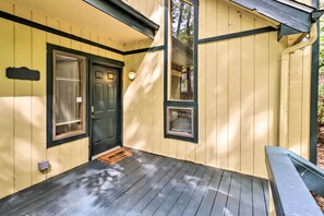 A wooden porch with a dark door, a small window, and a welcome mat.