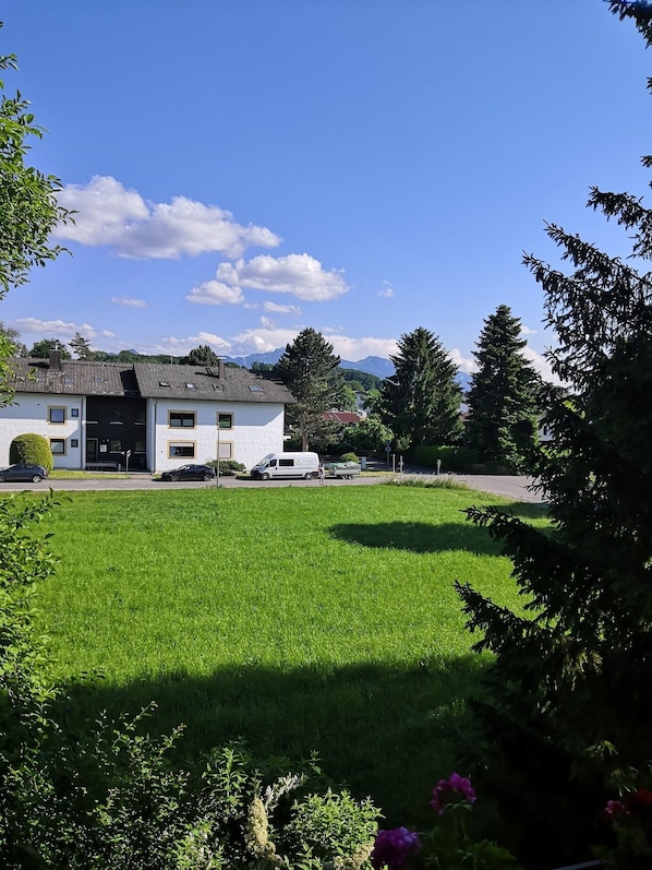 A residential area with a white house, a green lawn, and a mountain in the background.