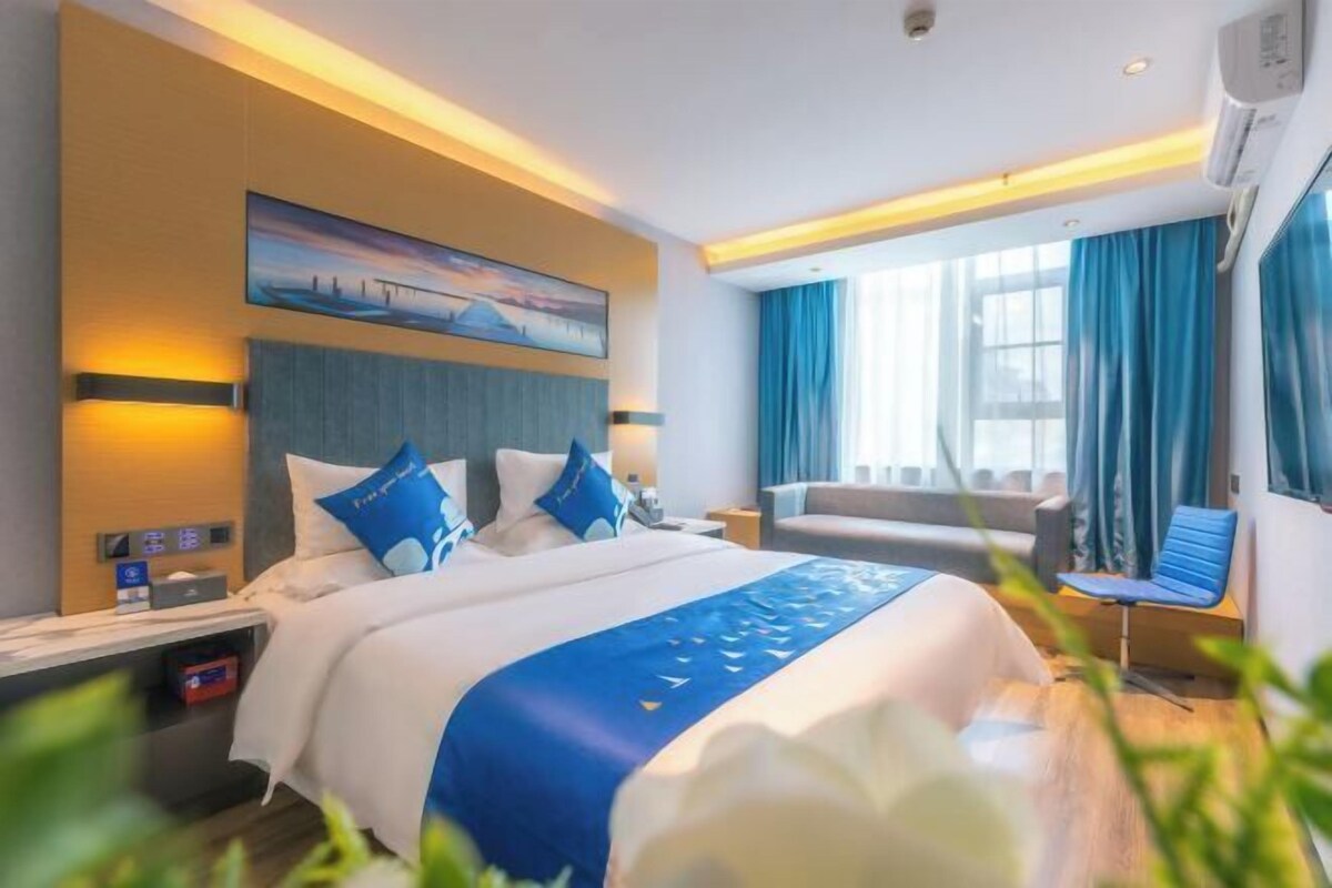 A modern hotel room with a large bed, a seating area, and a painting on the wall.