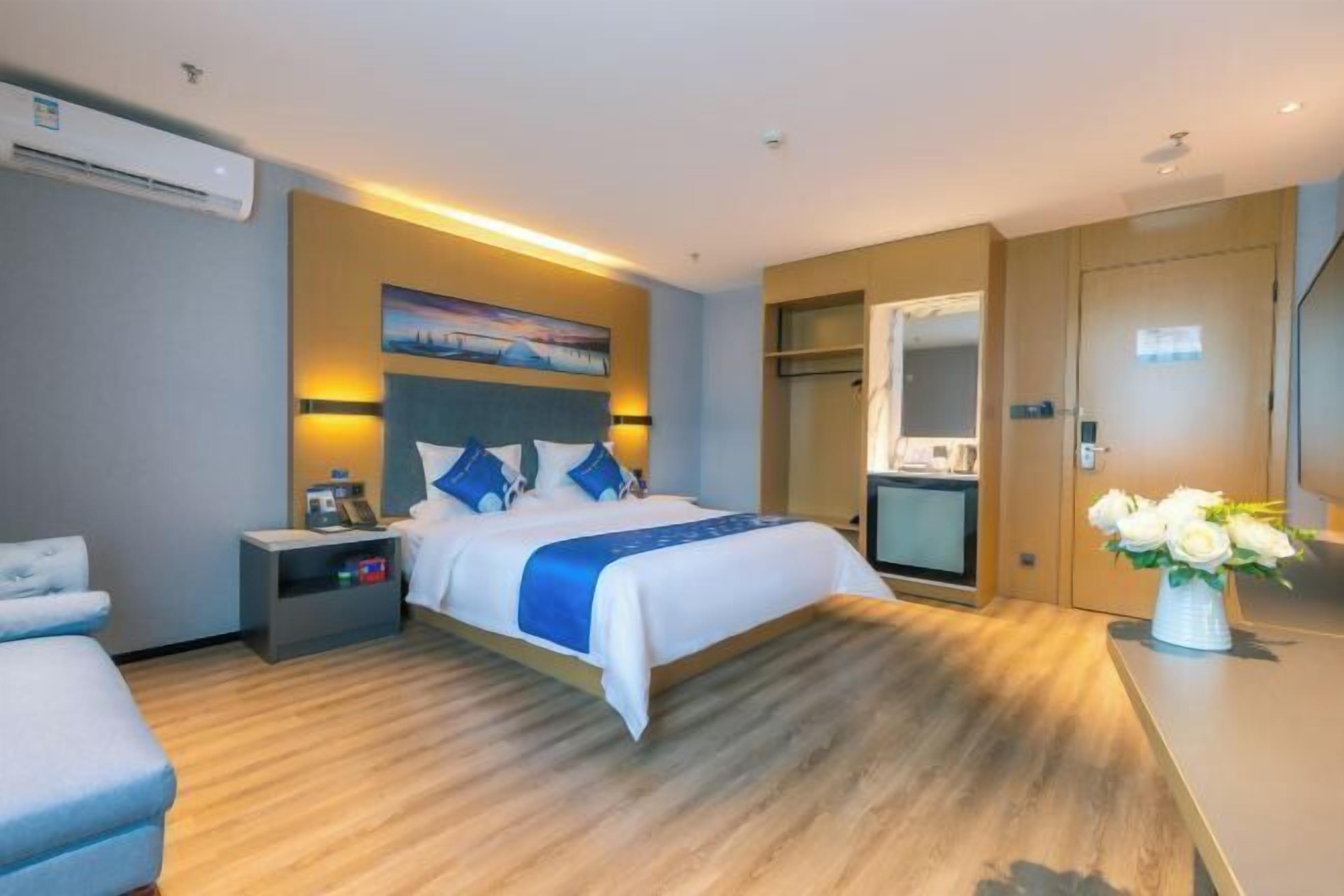 A modern hotel room with a large bed, bedside tables, a desk, and a mirror.