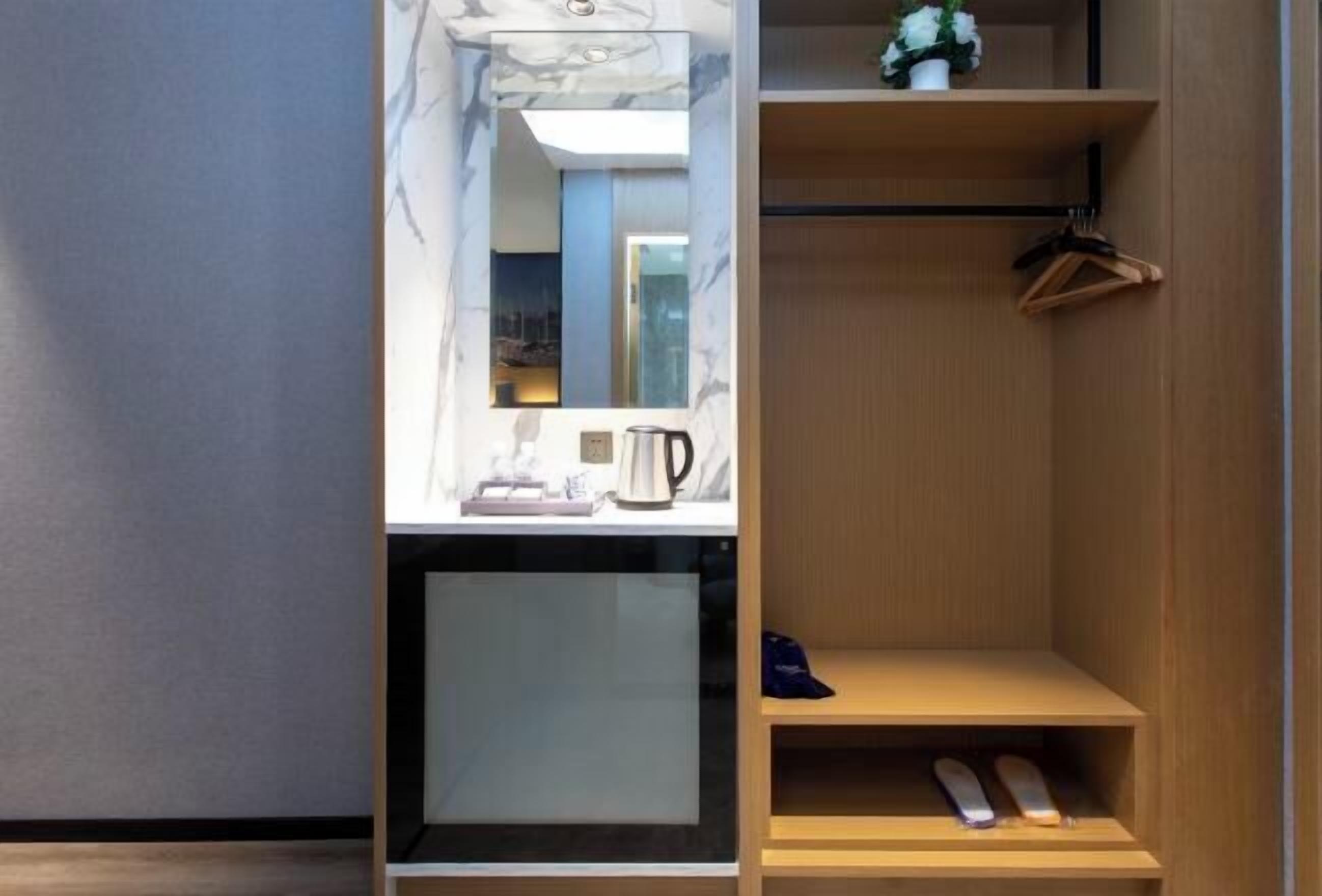 A modern bathroom with a marble vanity, a mirror, a coffee maker, and a wooden shelf with a hanger.